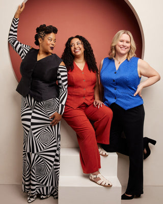 Three women posing together against a red and beige wall. This vest is the Hartwell Vest sewing pattern from Cashmerette.