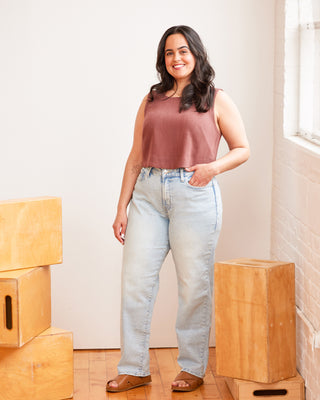 Woman wearing a sleeveless top and jeans standing in a room with wooden boxes. This top is the Thorndike Tank sewing pattern from Cashmerette.
