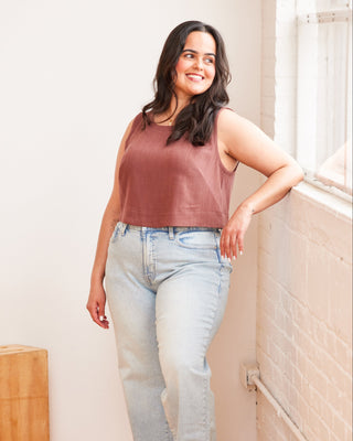 Woman wearing a sleeveless top and jeans standing against a light-colored wall. This top is the Thorndike Tank sewing pattern from Cashmerette.