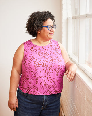 Woman wearing a pink floral top and blue jeans standing indoors. This top is the Thorndike Tank sewing pattern from Cashmerette.