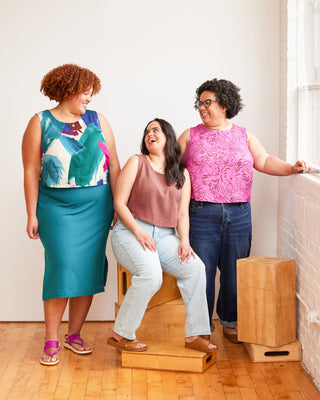 Three women posing together in a room with wooden flooring and white walls. This top is the Thorndike Tank sewing pattern from Cashmerette.