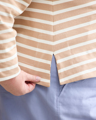 Close-up of a person wearing a beige and white striped top, pulling down the hem slightly with one hand, paired with light blue pants. This is the Wellfleet Breton T-Shirt sewing pattern from Cashmerette.