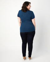 Woman wearing a blue shirt and black pants on a white background. This top is the Dartmouth Top sewing pattern from Cashmerette.