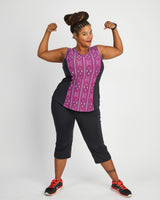 Woman flexing her muscles wearing a purple tank top and black capri pants on a white background. This top is the Spruce Workout Tank sewing pattern from Cashmerette.