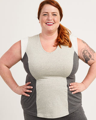 Woman wearing a gray and beige color-blocked sleeveless top on a white background. This top is the Spruce Workout Tank sewing pattern from Cashmerette.