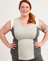 Woman wearing a gray and beige color-blocked sleeveless top on a white background. This top is the Spruce Workout Tank sewing pattern from Cashmerette.