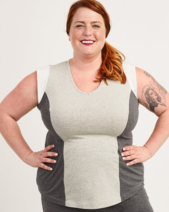 Woman wearing a gray and beige color-blocked sleeveless top on a white background. This top is the Spruce Workout Tank sewing pattern from Cashmerette.