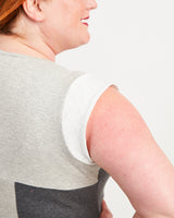 Woman wearing a gray tank top on a plain background. This top is the Spruce Workout Tank sewing pattern from Cashmerette.