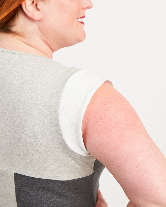 Woman wearing a gray tank top on a plain background. This top is the Spruce Workout Tank sewing pattern from Cashmerette.