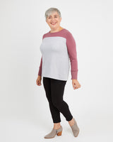 Person wearing a two-tone sweater with a white and pink design on a plain background. This sweater is the Tobin Sweater sewing pattern from Cashmerette.