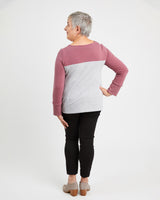 Person wearing a two-tone pink and gray sweater with black pants on a white background. This sweater is the Tobin Sweater sewing pattern from Cashmerette.
