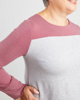 Person wearing a two-tone shirt with pink sleeves and a white body on a plain background. This sweater is the Tobin Sweater sewing pattern from Cashmerette.