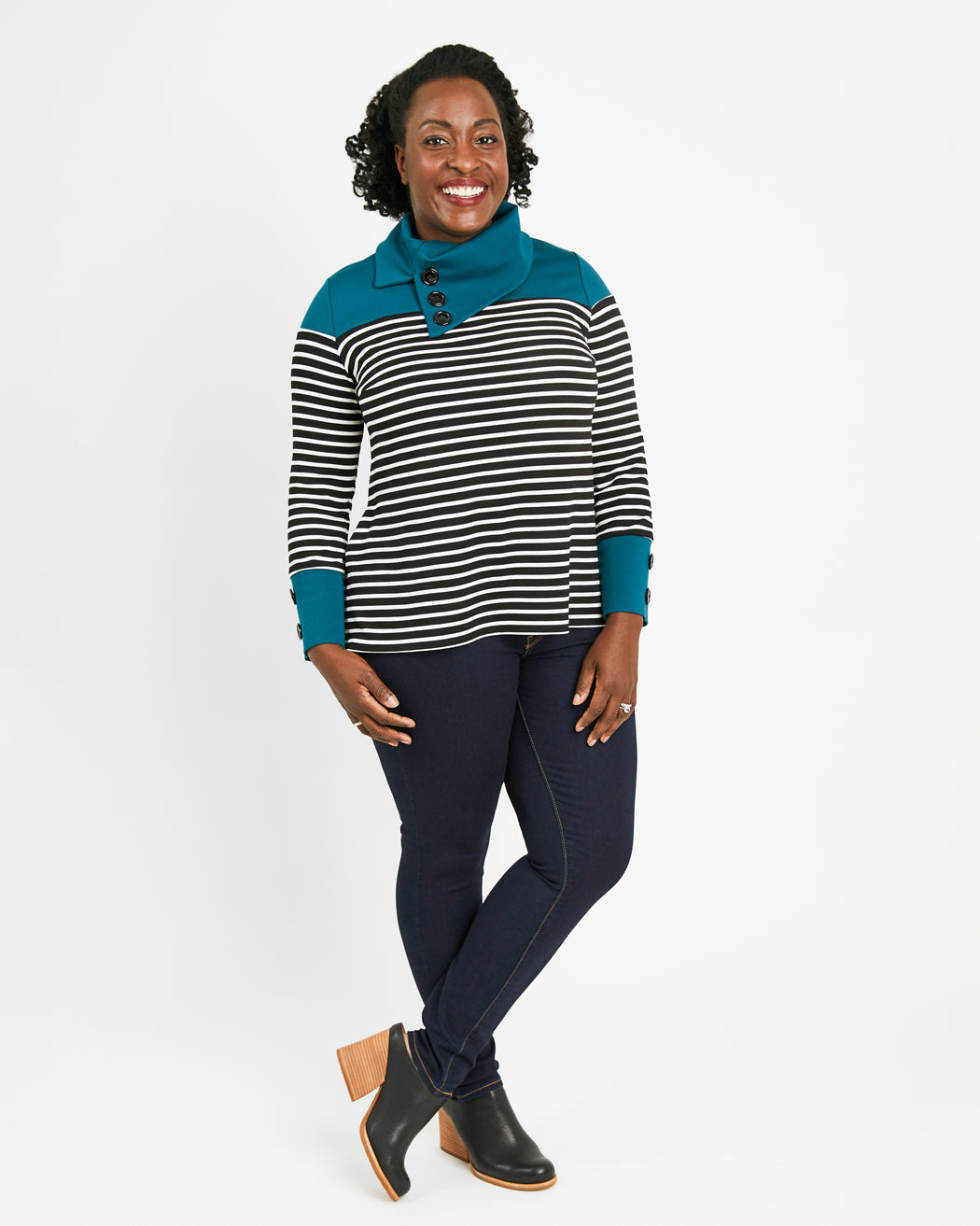 Woman wearing a striped sweater with teal accents on a white background. This sweater is the Tobin Sweater sewing pattern from Cashmerette.