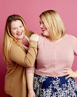 Two women posing together against a pink background. This cardigan is the Fuller Cardigan sewing pattern from Cashmerette.