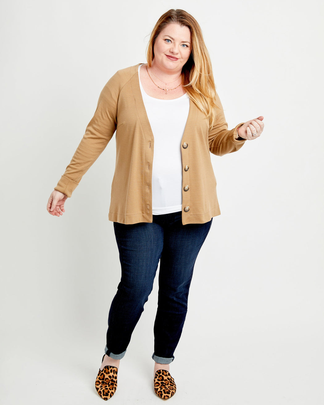 Woman wearing a beige cardigan, white shirt, and dark jeans on a light background. This cardigan is the Fuller Cardigan sewing pattern from Cashmerette.