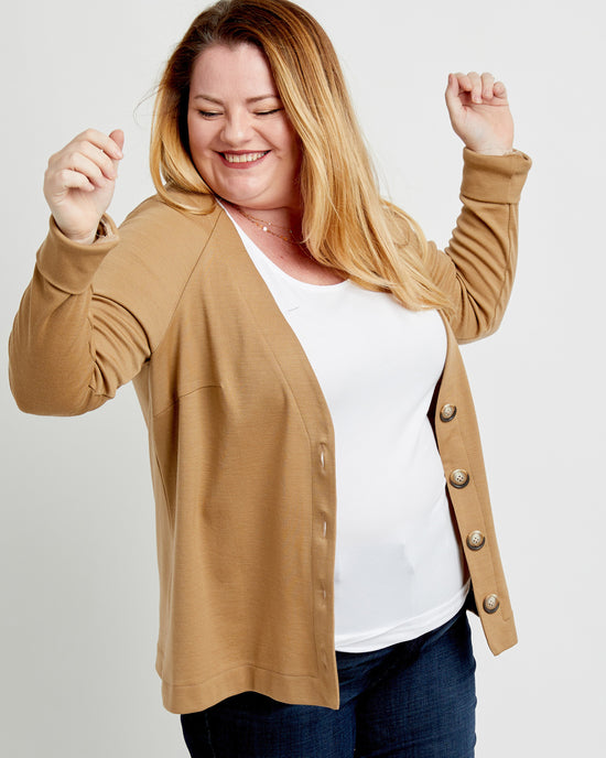 Woman wearing a brown cardigan over a white shirt on a plain background. This cardigan is the Fuller Cardigan sewing pattern from Cashmerette.