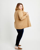 Woman wearing a beige sweater and dark jeans on a white background. This cardigan is the Fuller Cardigan sewing pattern from Cashmerette.