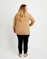 Woman wearing a beige sweater and dark pants on a white background. This cardigan is the Fuller Cardigan sewing pattern from Cashmerette.