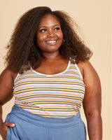 Woman wearing a striped tank top and blue pants against a beige background. This tank top is the Saybrook Tank sewing pattern from Cashmerette.
