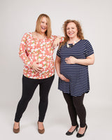Two women standing side by side, one wearing a floral top and black pants, the other in a striped top and black pants, on a plain background. This t-shirt is the Brookline Maternity T-Shirt sewing pattern from Cashmerette.