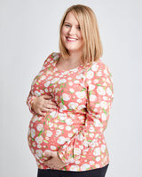 Pregnant woman wearing a pink floral patterned top on a white background. This t-shirt is the Brookline Maternity T-Shirt sewing pattern from Cashmerette.