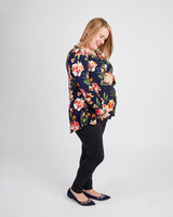 Woman wearing a floral top and black pants on a white background. This t-shirt is the Brookline Maternity T-Shirt sewing pattern from Cashmerette.