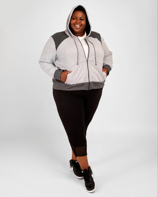 Person wearing a gray and black hoodie with black leggings on a white background. This hoodie is the Stanton Hoodie sewing pattern from Cashmerette.