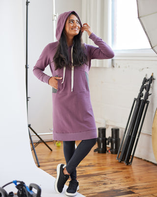 Woman wearing a purple hoodie dress in a studio setting. This hoodie is the Stanton Hoodie sewing pattern from Cashmerette.