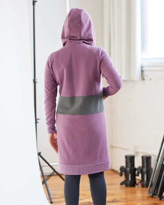 Person wearing a purple hoodie with a gray stripe in an indoor setting. This hoodie is the Stanton Hoodie sewing pattern from Cashmerette.