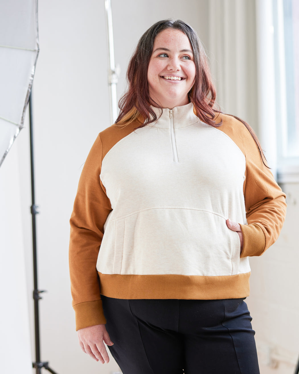 Person wearing a white and brown half-zip sweatshirt in an indoor setting. This hoodie is the Stanton Hoodie sewing pattern from Cashmerette.