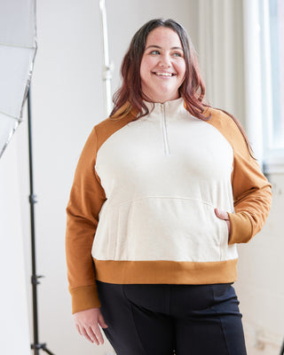 Person wearing a white and brown half-zip sweatshirt in an indoor setting. This hoodie is the Stanton Hoodie sewing pattern from Cashmerette.