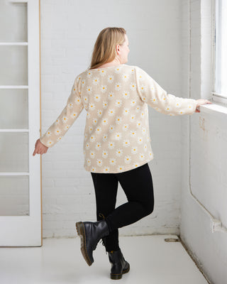 Woman wearing a floral blouse and black pants standing in a room with white walls. This is the Wexford Top & Dress sewing pattern from Cashmerette.