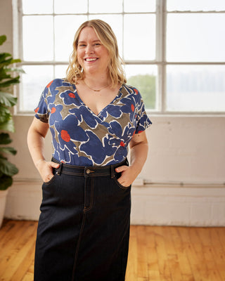 Woman wearing a colorful floral blouse standing in a room with large windows. This top is the Kenwin Raglan T-Shirt sewing pattern from Cashmerette.