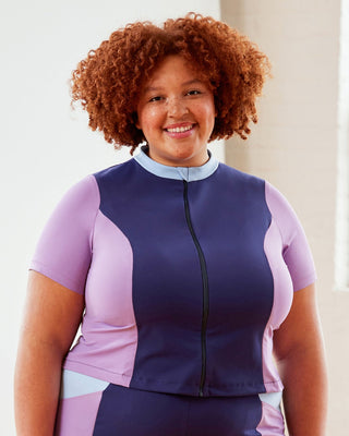 Person wearing a purple and navy cycling outfit with a white background. This top is the Bonair Athletic Top sewing pattern from Cashmerette.