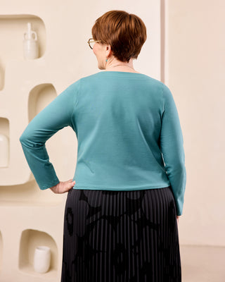 Woman posing with her back to the camera. She's wearing a teal top and black skirt. This is the Amesbury Cowl Top sewing pattern from Cashmerette.