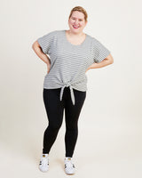 Woman wearing a striped shirt and black leggings on a white background. This top is the Cedar Dolman Top sewing pattern from Cashmerette.