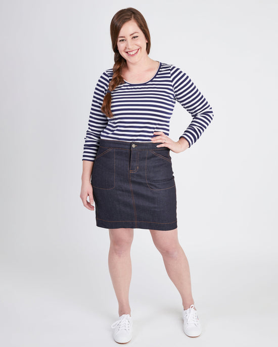 Woman wearing a striped shirt and denim skirt on a white background. This skirt is the Ellis Denim Skirt sewing pattern from Cashmerette.
