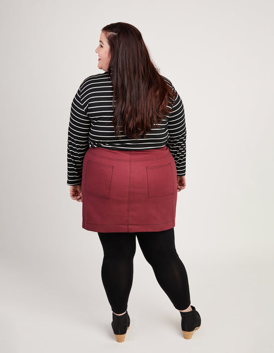 Person wearing a black and white striped shirt with a red skirt on a plain background. This skirt is the Ellis Denim Skirt sewing pattern from Cashmerette.
