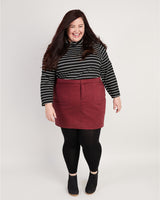 Woman wearing a striped shirt and red skirt on a white background. This skirt is the Ellis Denim Skirt sewing pattern from Cashmerette.