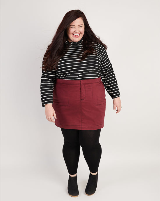 Woman wearing a striped shirt and red skirt on a white background. This skirt is the Ellis Denim Skirt sewing pattern from Cashmerette.