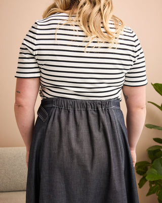 Person wearing a black and white striped shirt and dark denim skirt against a beige wall. This is the Osgood Skirt sewing pattern from Cashmerette.
