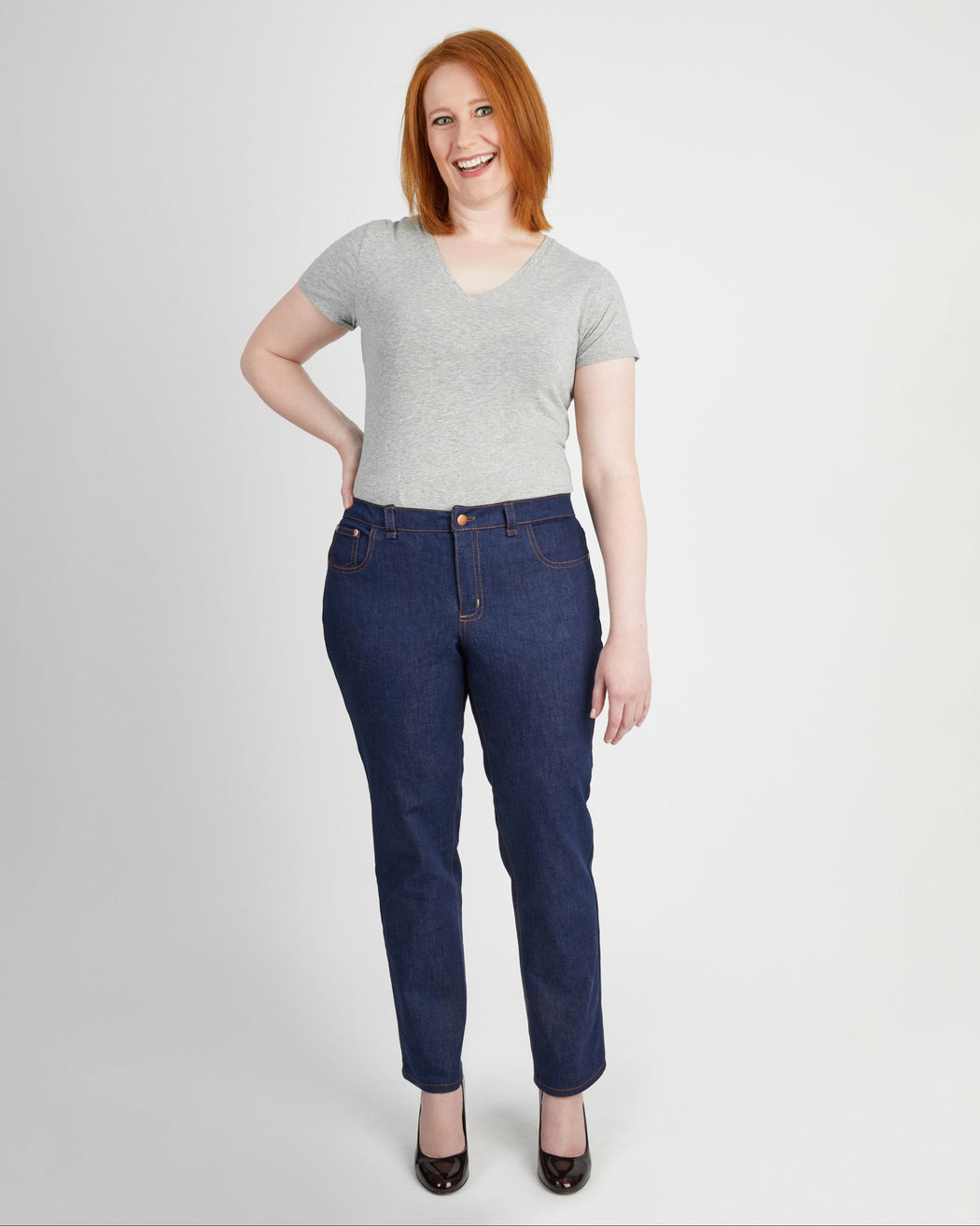 Woman wearing a gray t-shirt and blue jeans on a white background. These jeans are the Ames Jeans sewing pattern from Cashmerette.