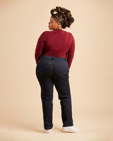 Person wearing a red top and dark jeans on a beige background. These jeans are the Ames Jeans sewing pattern from Cashmerette.