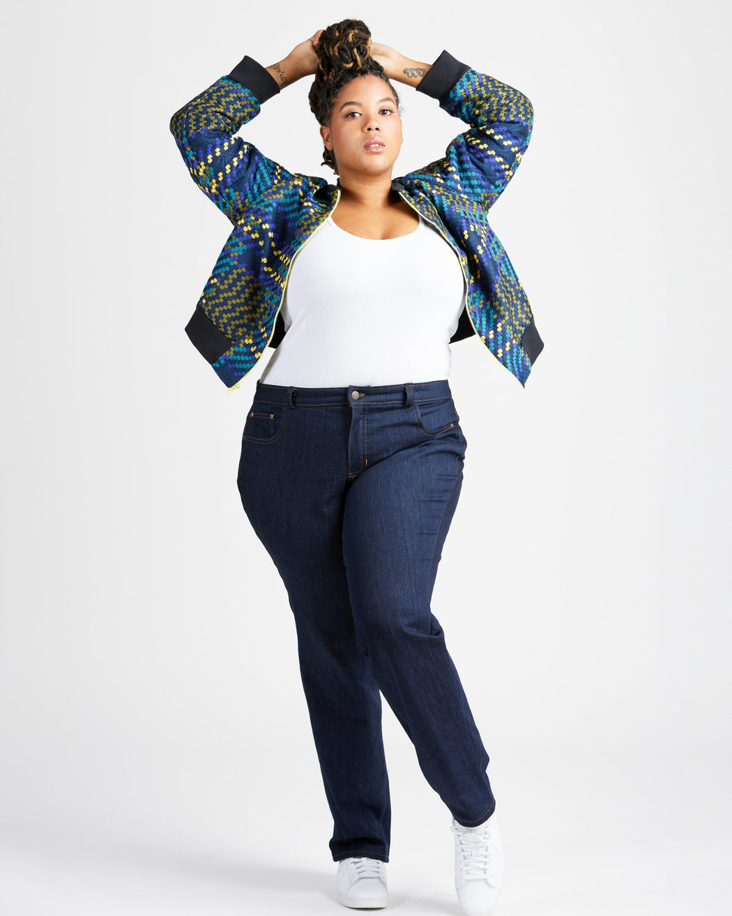 Person wearing a patterned jacket, white shirt, and dark jeans on a white background. These jeans are the Ames Jeans sewing pattern from Cashmerette.