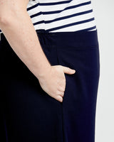 Navy pants worn with a striped shirt on a plain background. These pants are the Calder Pants & Shorts sewing pattern from Cashmerette.