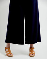 Person wearing navy blue pants and brown sandals on a white background. These pants are the Calder Pants & Shorts sewing pattern from Cashmerette.