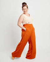 Woman wearing a beige top and orange wide-leg pants on a white background. These pants are the Calder Pants & Shorts sewing pattern from Cashmerette.