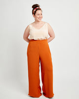 Woman wearing a beige top and orange pants on a white background. These pants are the Calder Pants & Shorts sewing pattern from Cashmerette.