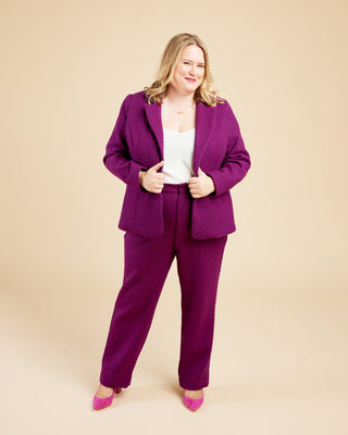 Woman wearing a purple suit on a beige background. These pants are the Meriam Trousers sewing pattern from Cashmerette.