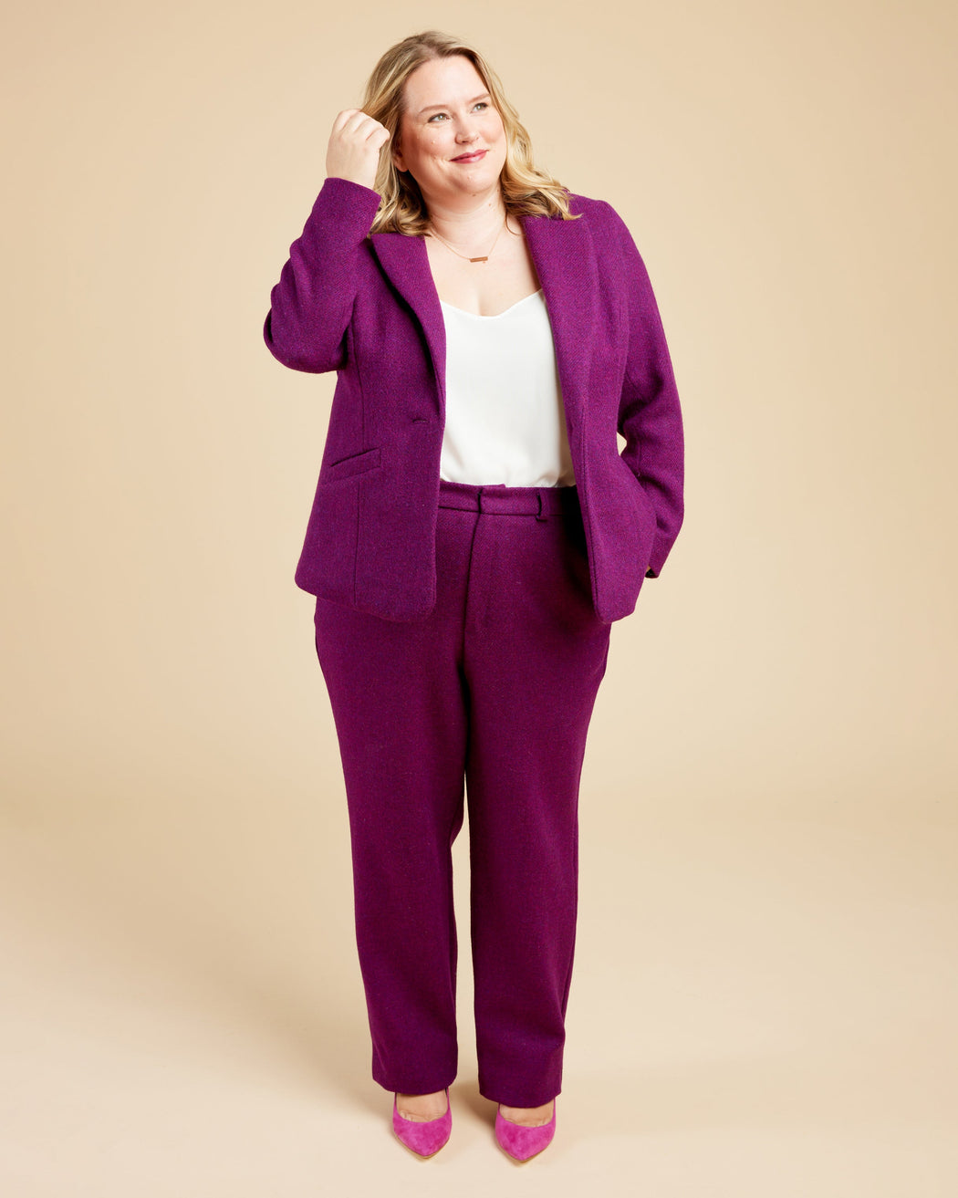 Woman wearing a purple suit with a beige background. These pants are the Meriam Trousers sewing pattern from Cashmerette.